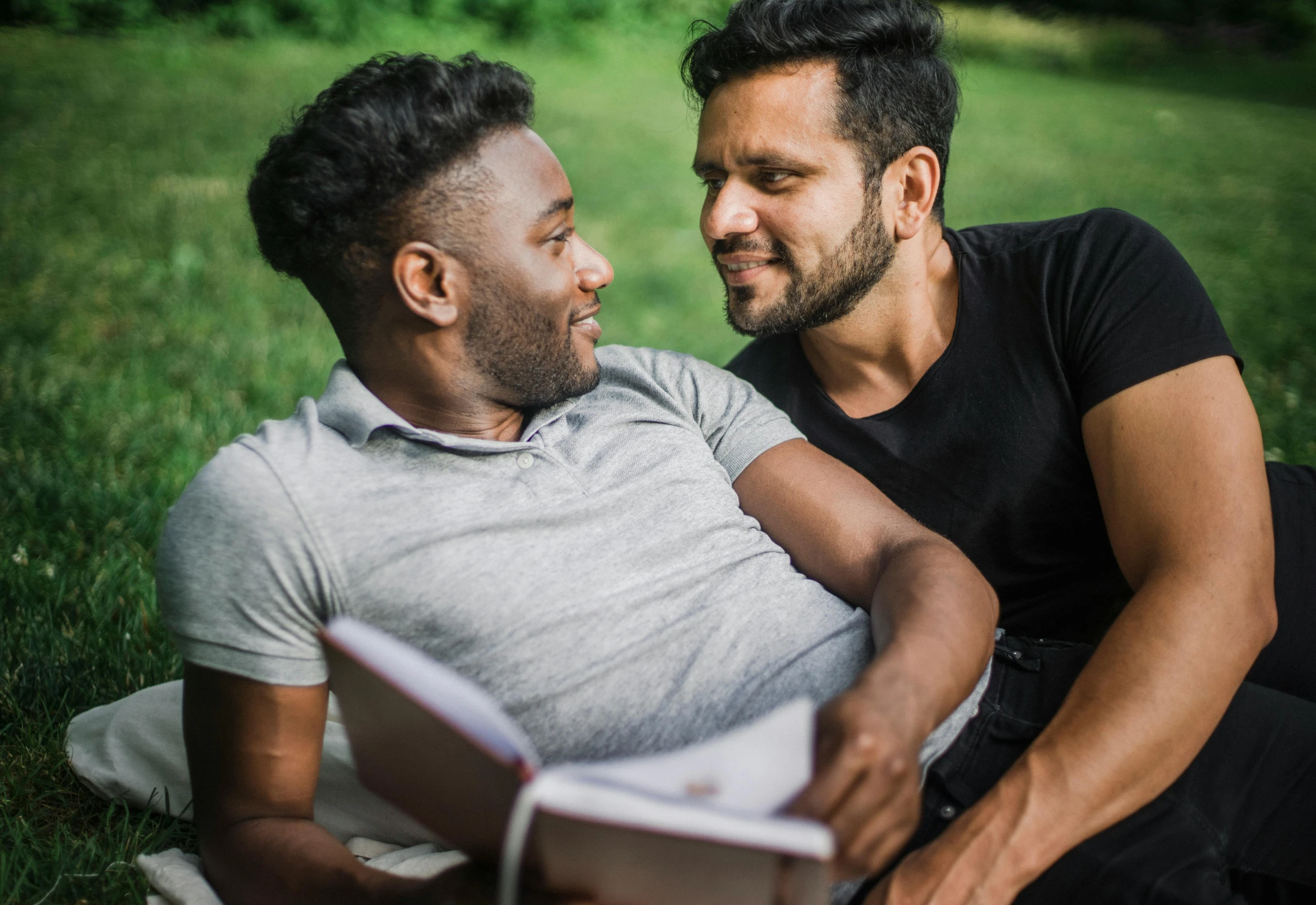 two men are sitting down reading a book