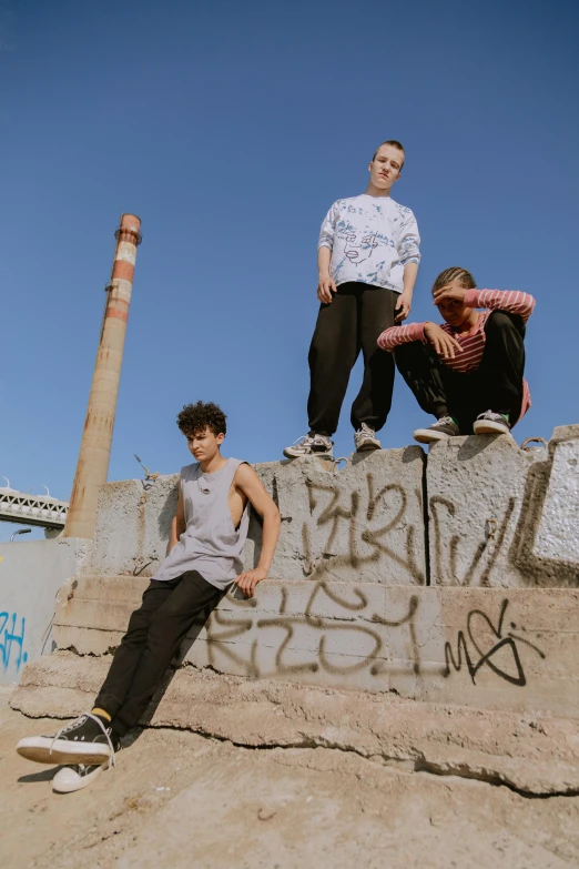 three skateboarders are posing against an old brick wall