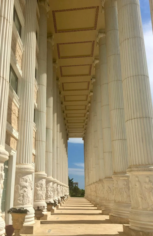 a row of white pillars sitting next to a sky filled with clouds