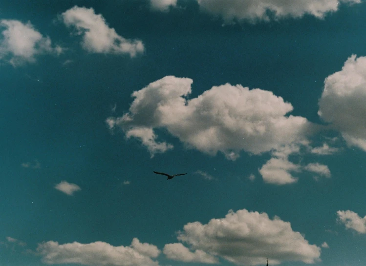 an airplane flying under a partly cloudy blue sky