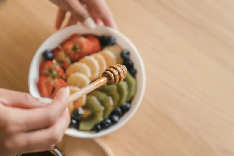 the bowls are filled with colorful fruit and a gold honey dipped stick