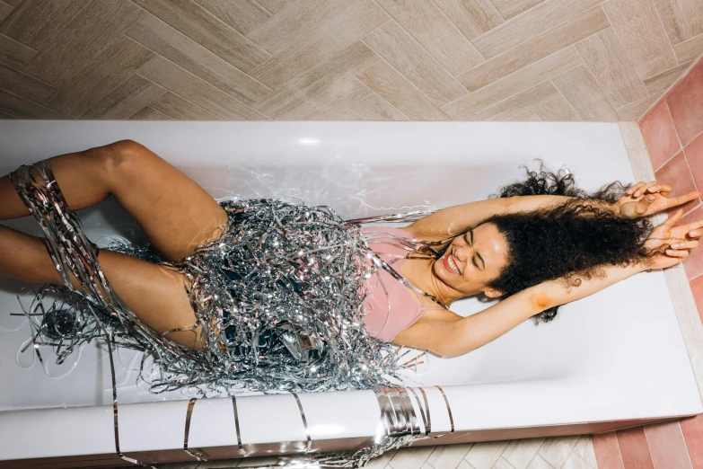 a woman sitting in a tub filled with silver hair