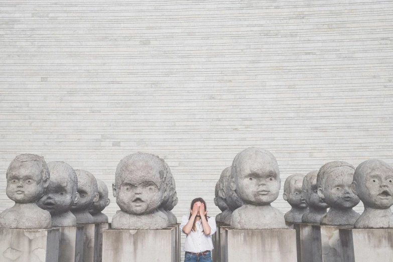 an adorable little girl stands between several statues