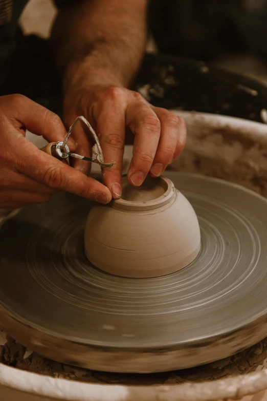 a man is knring a piece of pottery on top of a wheel