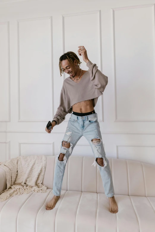 a woman standing on a couch wearing ripped jeans