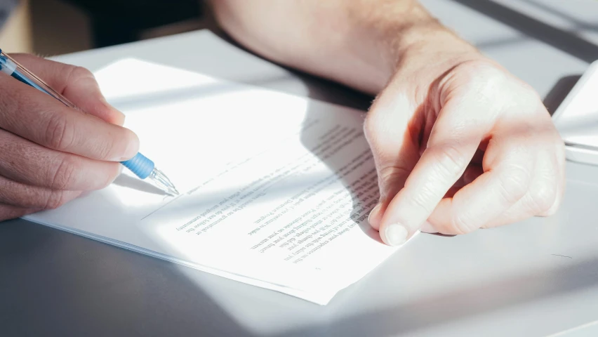 someone sitting at a desk with a pen and a notepad in their hand