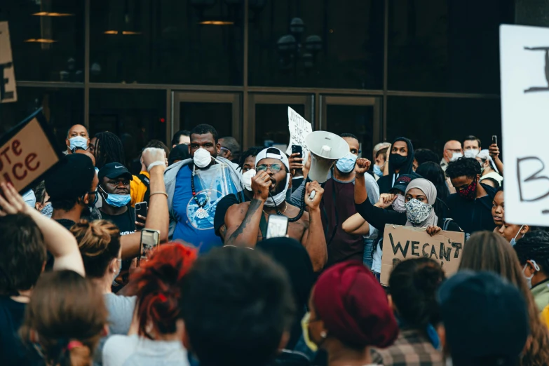 a group of people holding protest signs and wearing masks