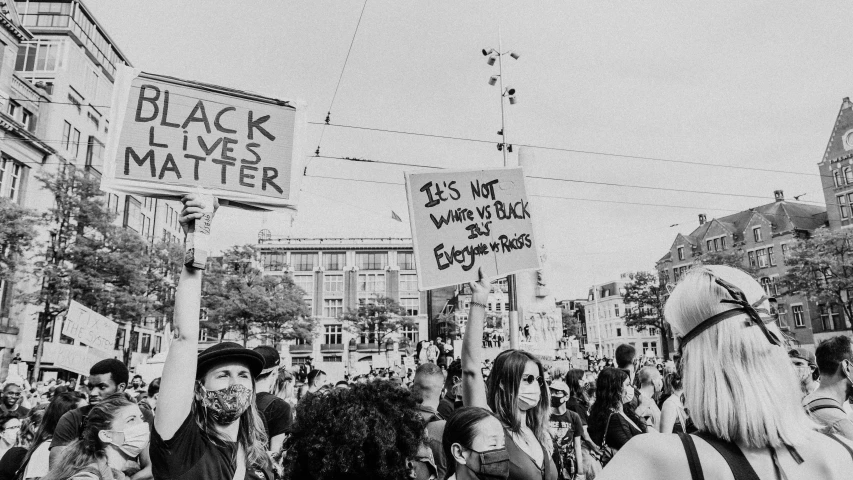 people with black and white portraits on their backs holding up signs in the air