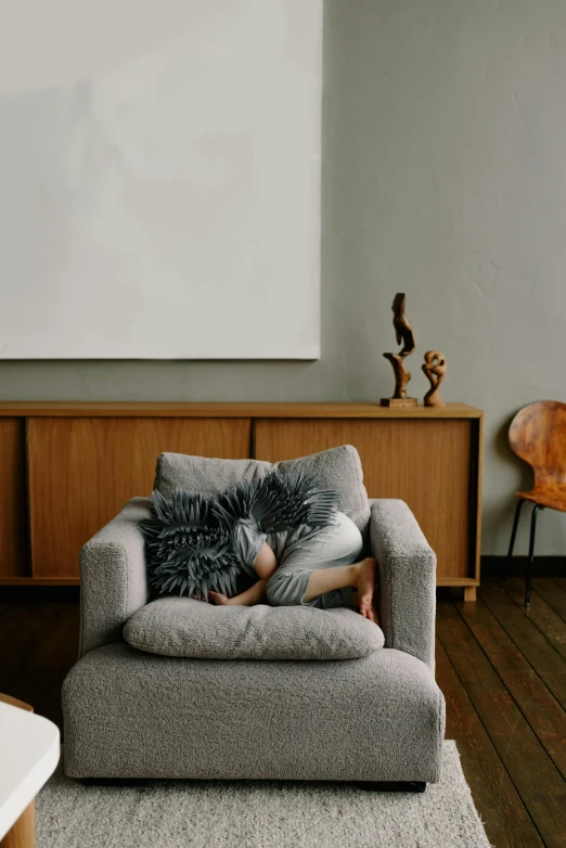 a person laying on top of a gray couch