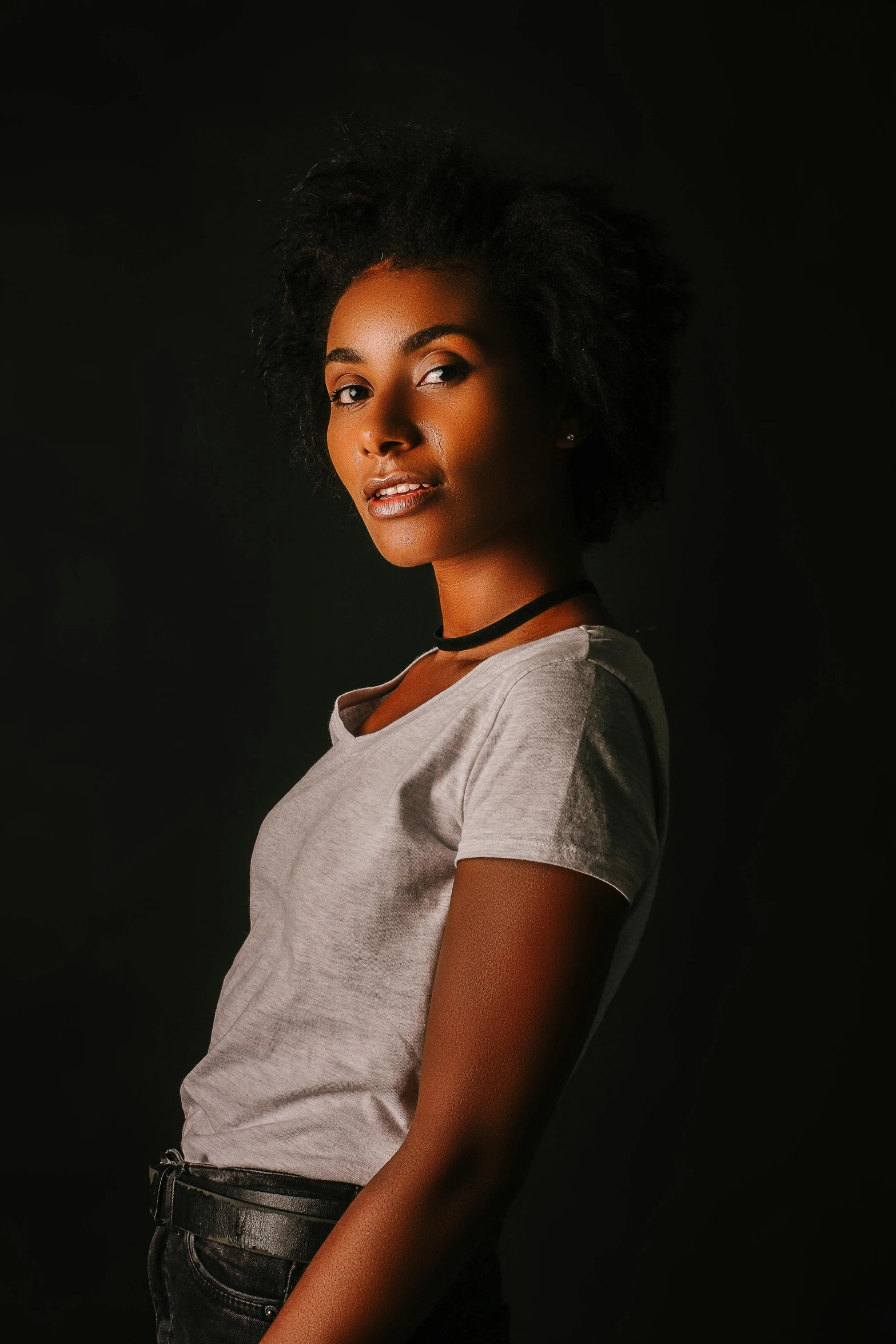 a woman smiling in the dark with her arms on the waist