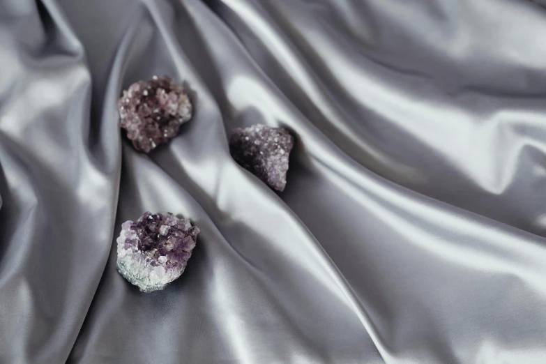some purple, silver, and white crystals sitting on a silver satin