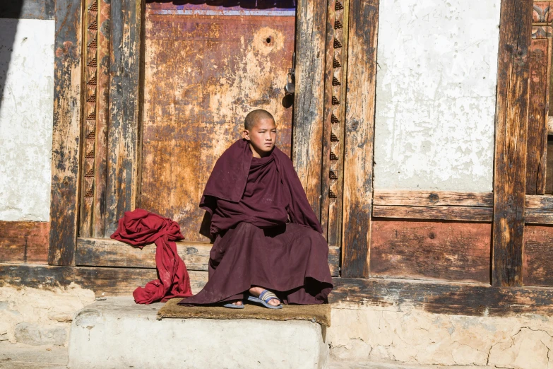 a person sitting down and wearing a brown robe