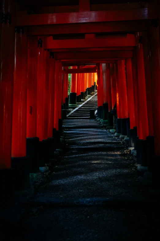 a walkway lined with tall red columns with light shining down them