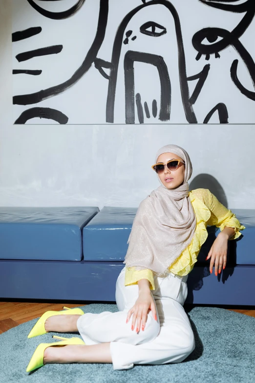 a woman wearing a yellow shirt sits on the floor