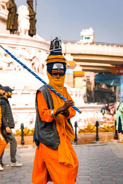 a man in orange is holding a stick