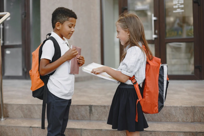 two young students are holding school supplies on a set of steps