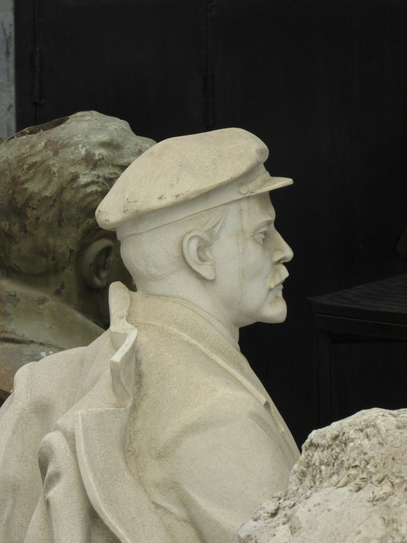 two statues, one wearing a white coat and one wearing a hat