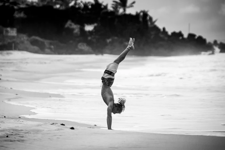 a young woman is doing a handstand on the beach