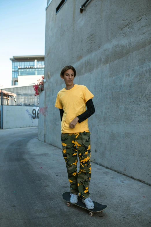 a boy standing on a skateboard with arms around his waist