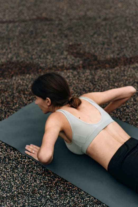 a woman is laying on her stomach while working out on a yoga mat