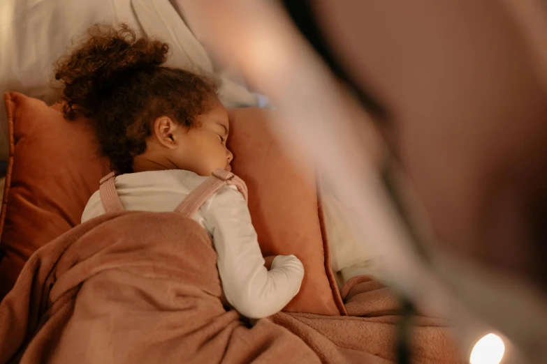 a little girl in a white shirt sleeping on top of a orange pillow