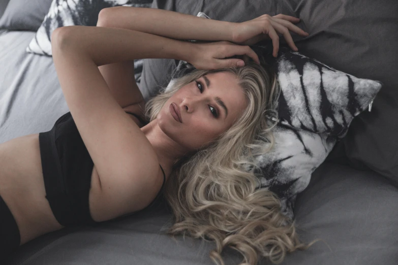 the blonde woman in the black  laying on the bed