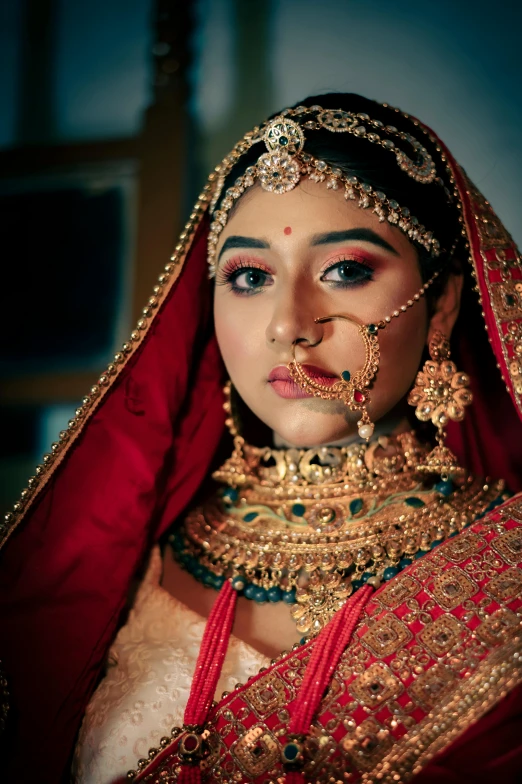 the woman is wearing a red veil and gold jewelry