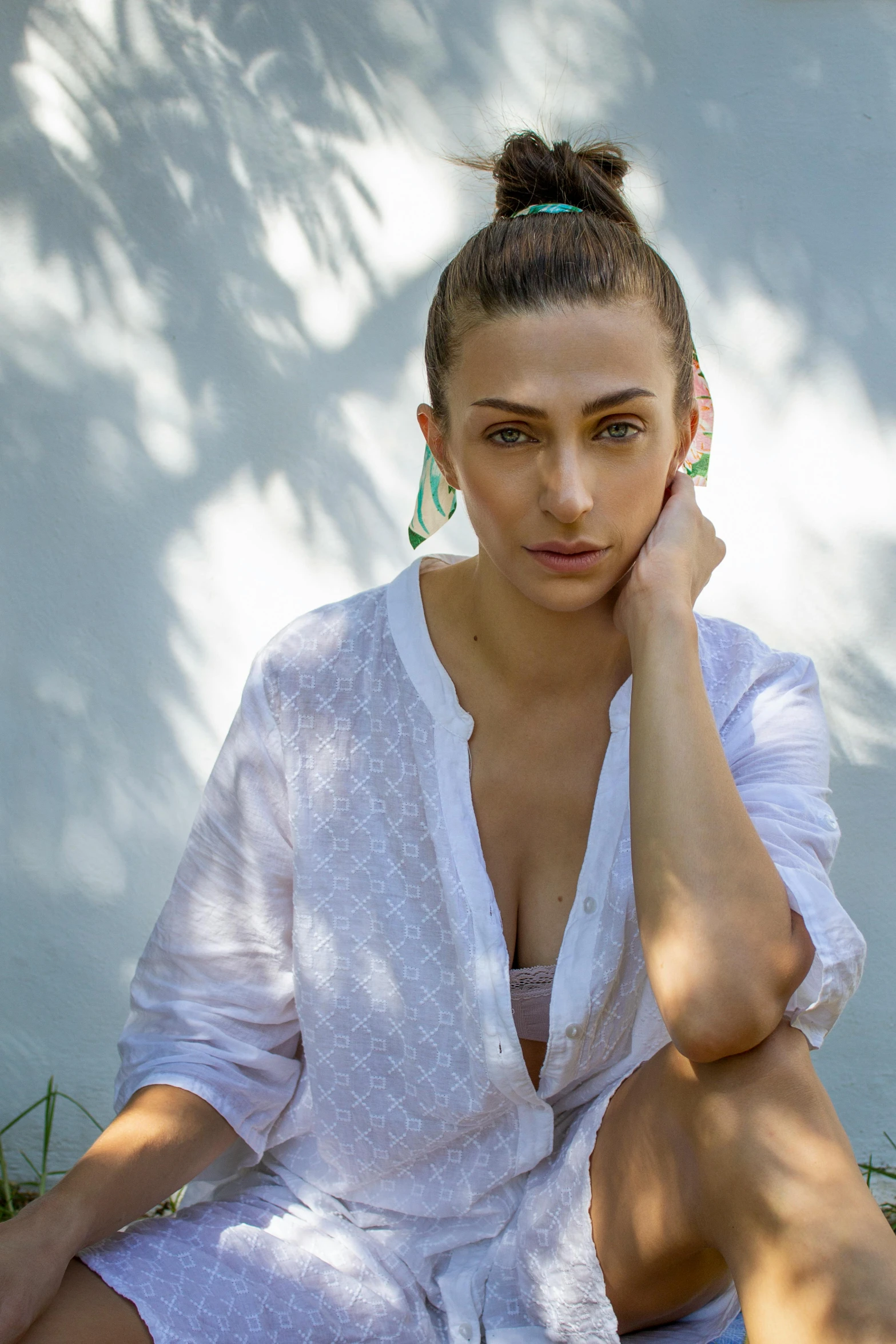 a woman wearing earrings sits against a wall