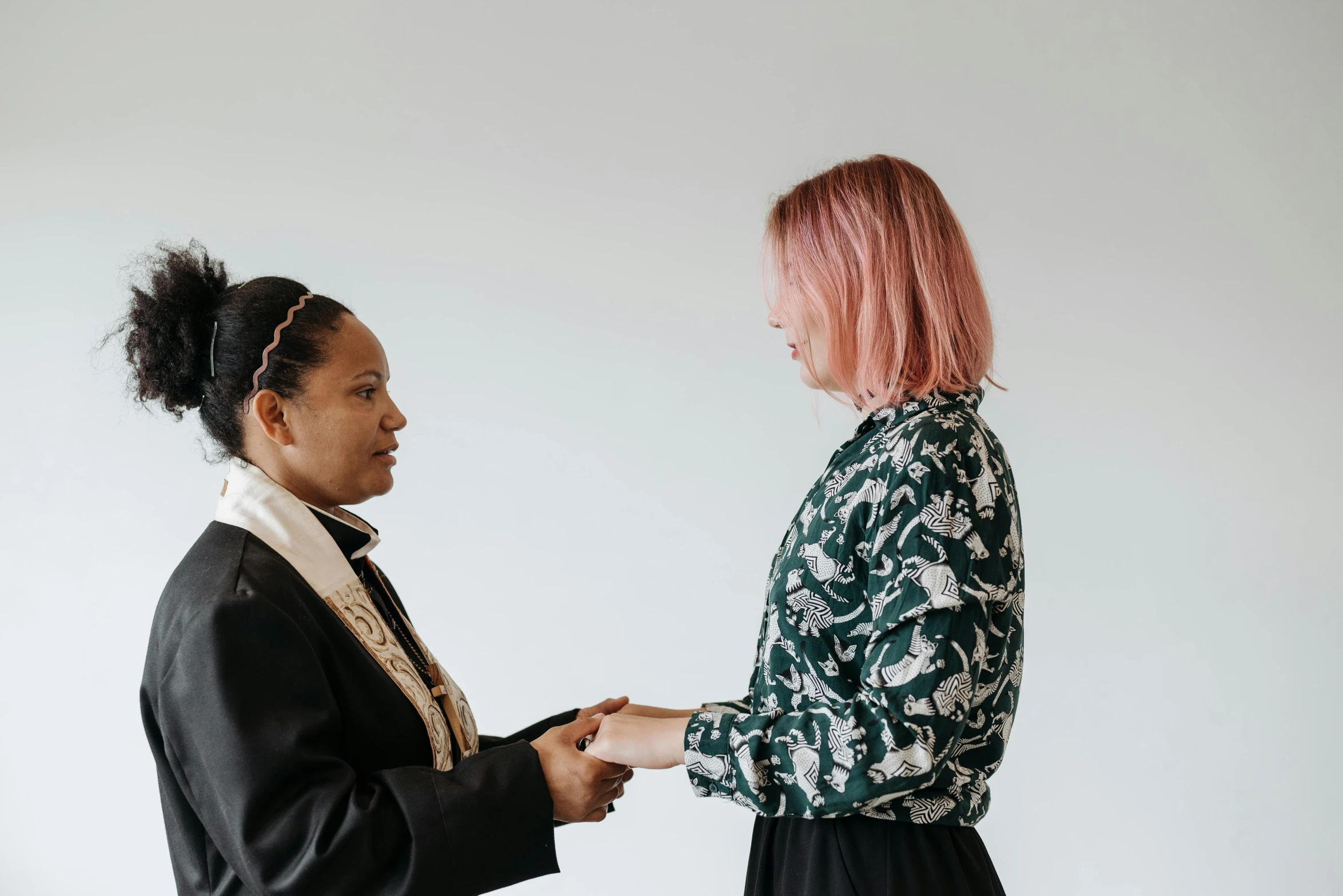 two women are facing each other and one is holding hands