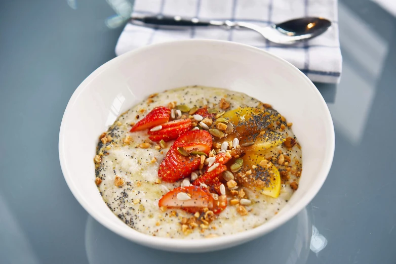 a close up of a bowl of oatmeal with strawberries and nuts