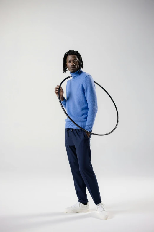 a man in blue sweater standing with large black plastic hoop