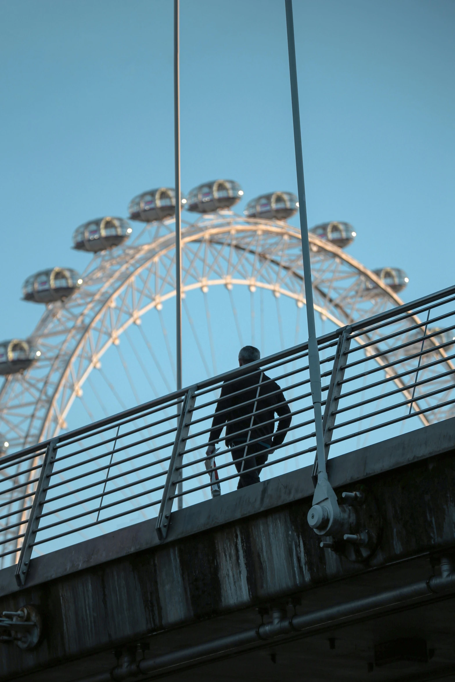 a person standing on the bridge over looking a ferris wheel