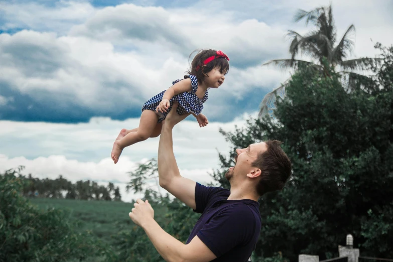 a man and his daughter playing outside under a cloudy sky