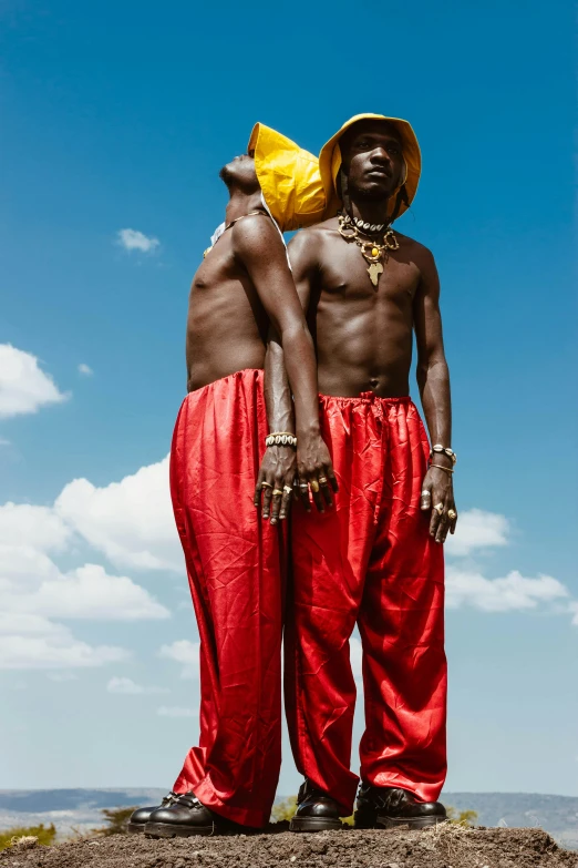 two men dressed in red are standing on a rock