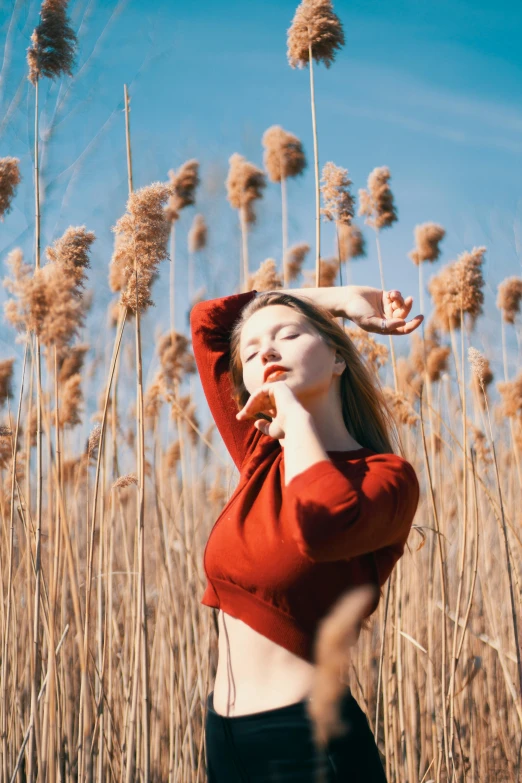 a girl standing in the middle of a field with long grass