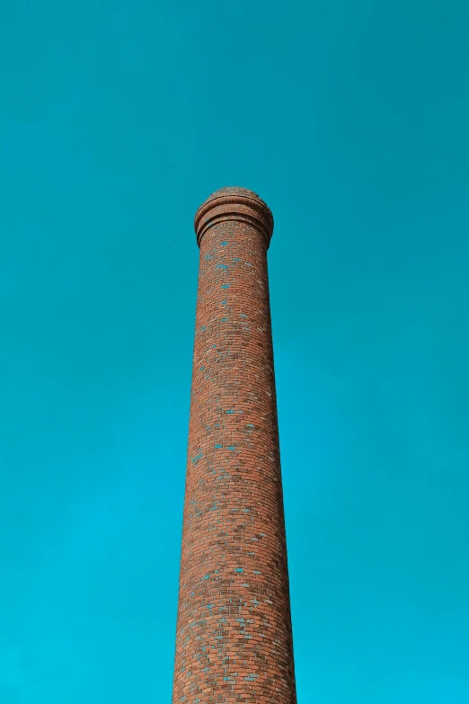 a tall brick chimney stands against a blue sky