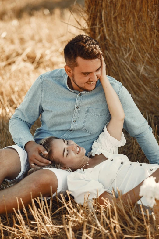 a young couple sitting together, emcing, on a field