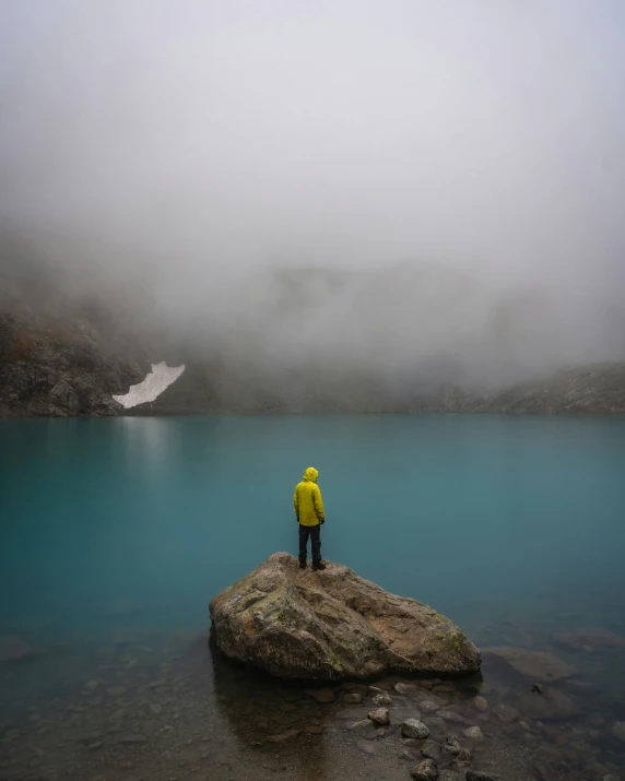 a man standing on top of a rock in front of water