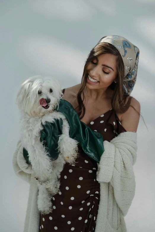 a woman holding a small dog wearing a hat