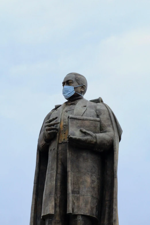 a large statue wearing a mask and holding a book in his hands