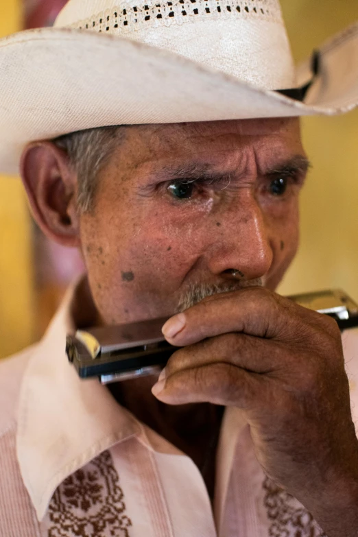 a man with a moustache and white hat, chewing on a pipe