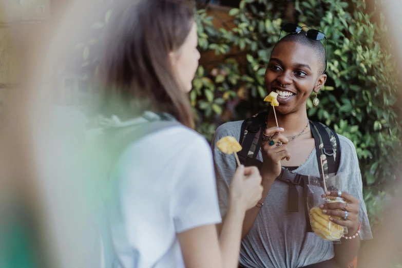 two female friends eating outside together smiling