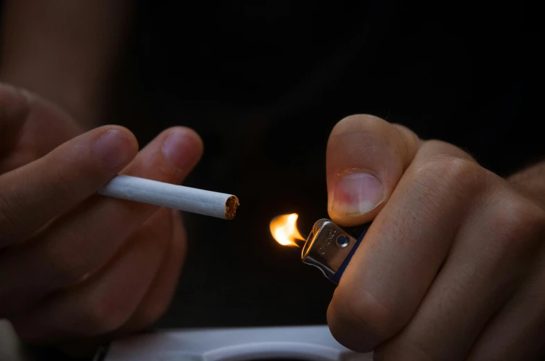 person holding cigarette lighter and smoking cigarette