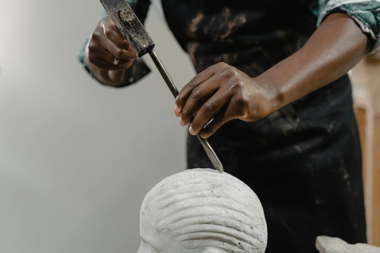 the man is carving the white head and using scissors