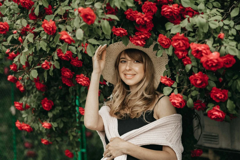 a woman smiles as she holds a hat over her shoulders