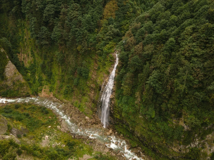 waterfall near a mountain side surrounded by green vegetation