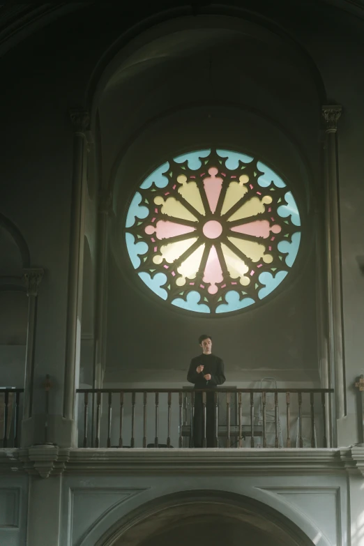 man at the top of a balcony looking at stain glass