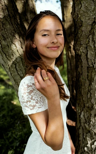 a smiling woman in a wedding dress next to a tree