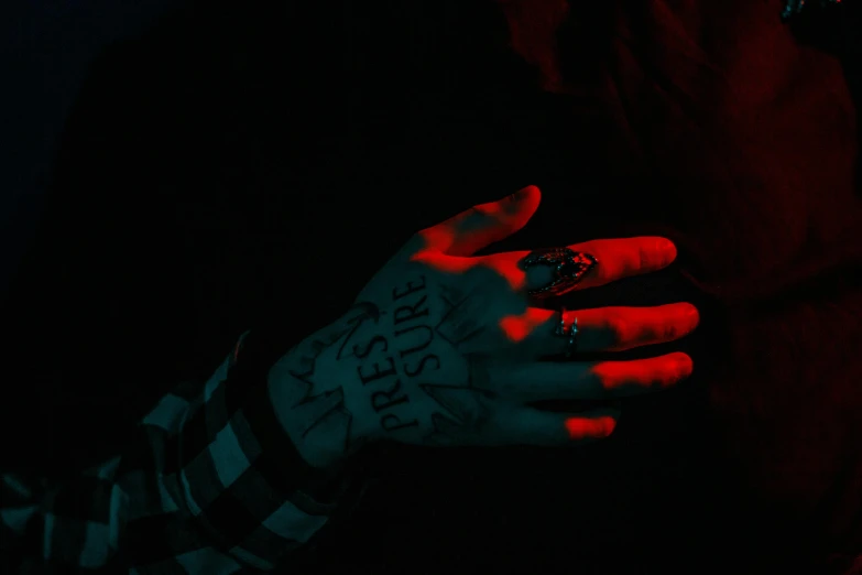 a woman with tattoos holds her hand in the dark