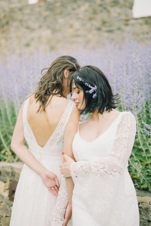 a bride with her back to the camera standing next to her friend in front of lavenders